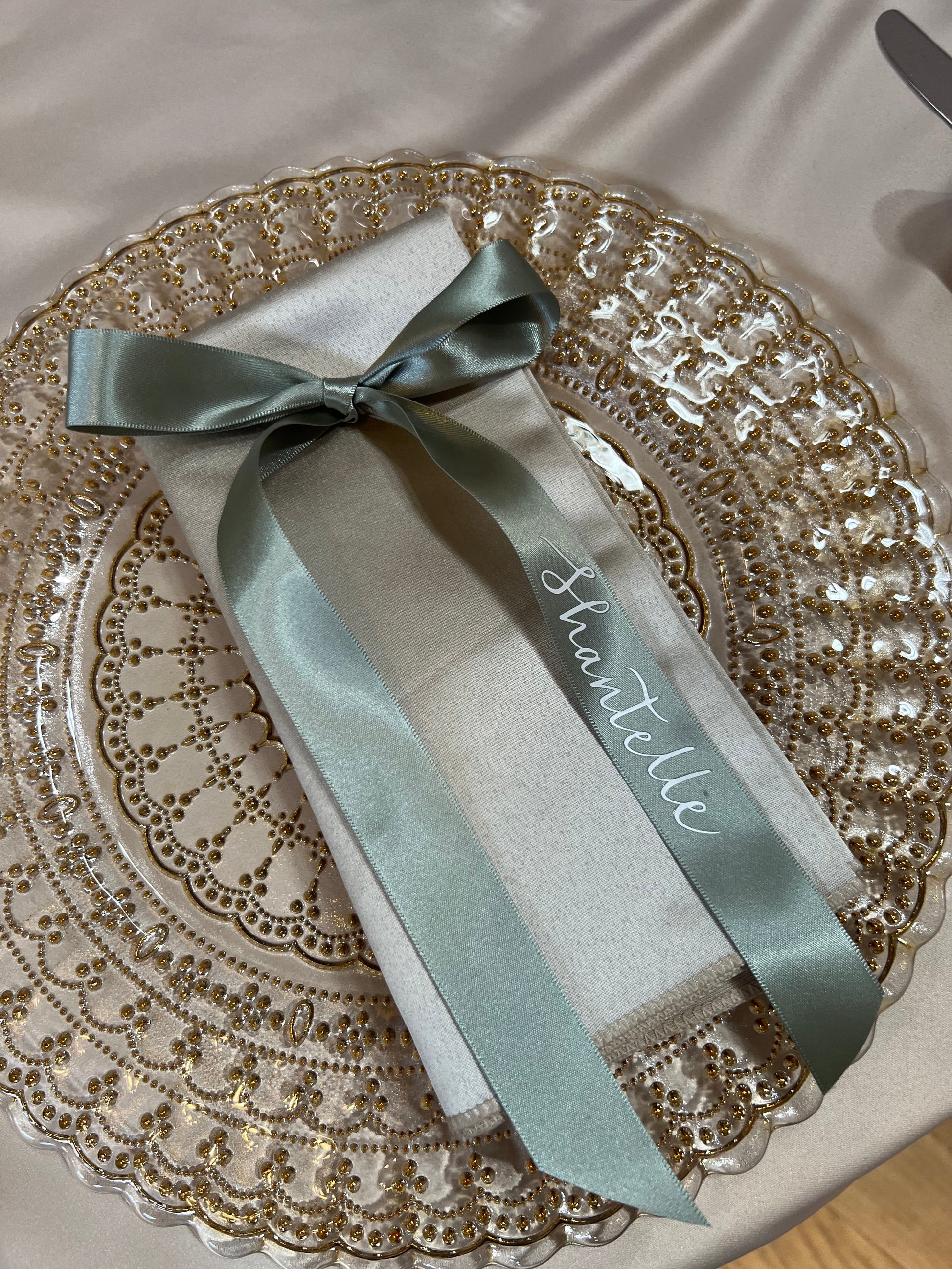 Green ribbon personalised place card on a gold plate
