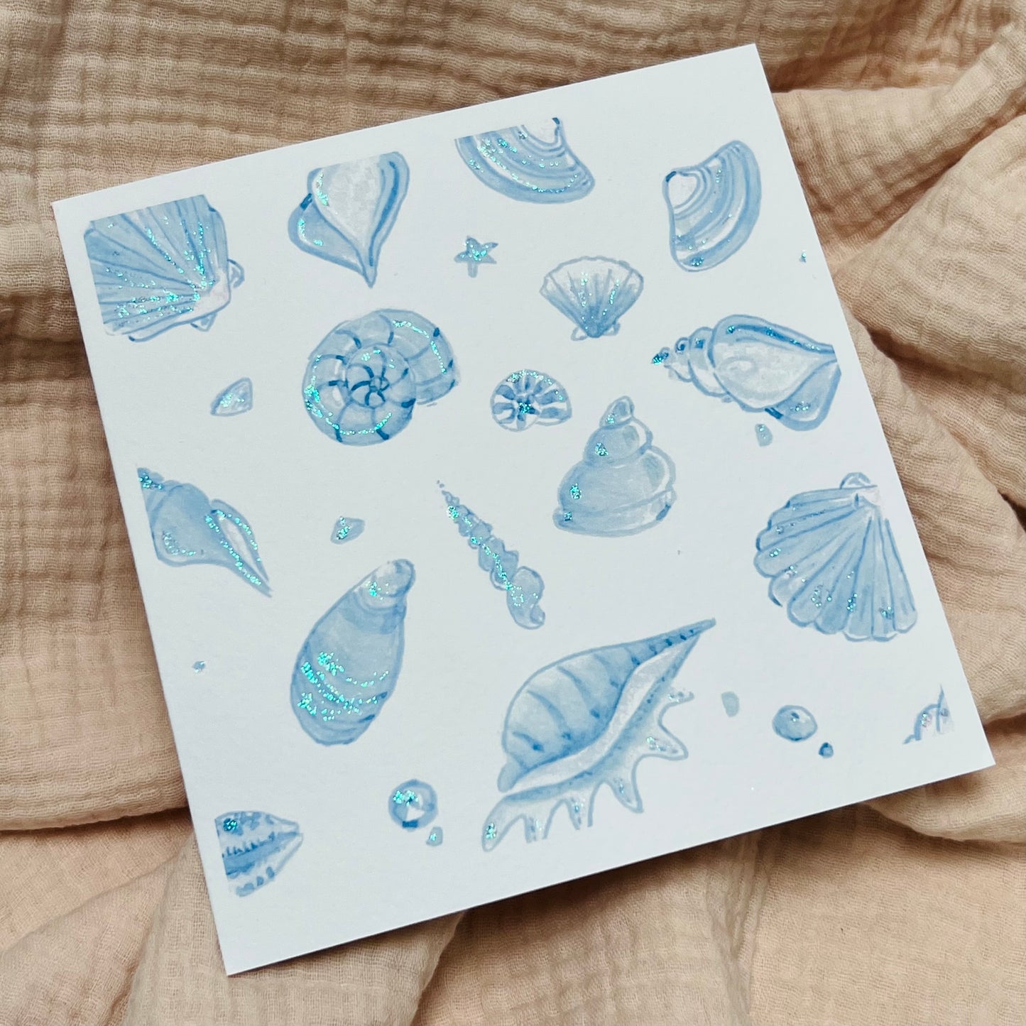 shimmering greetings card with lots of blue shells and sparkling with glitter.