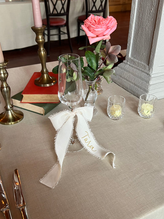 White personalised calligraphy ribbon bow on champagne flute