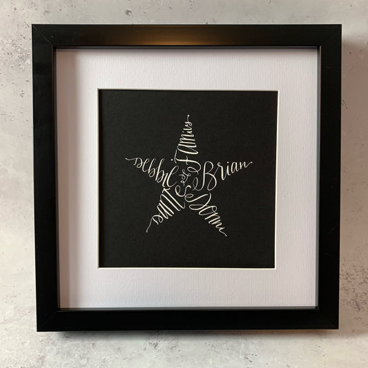 black frame with white mount, filled with black card and calligraphy star in white ink made up of names. Fully personalised with five names or words