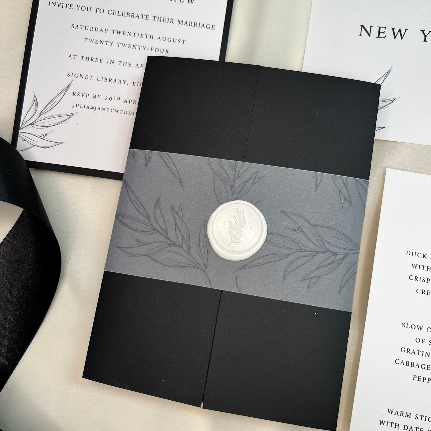 Black gatefold card with printed foliage velllum cuff and white foliage wax seal