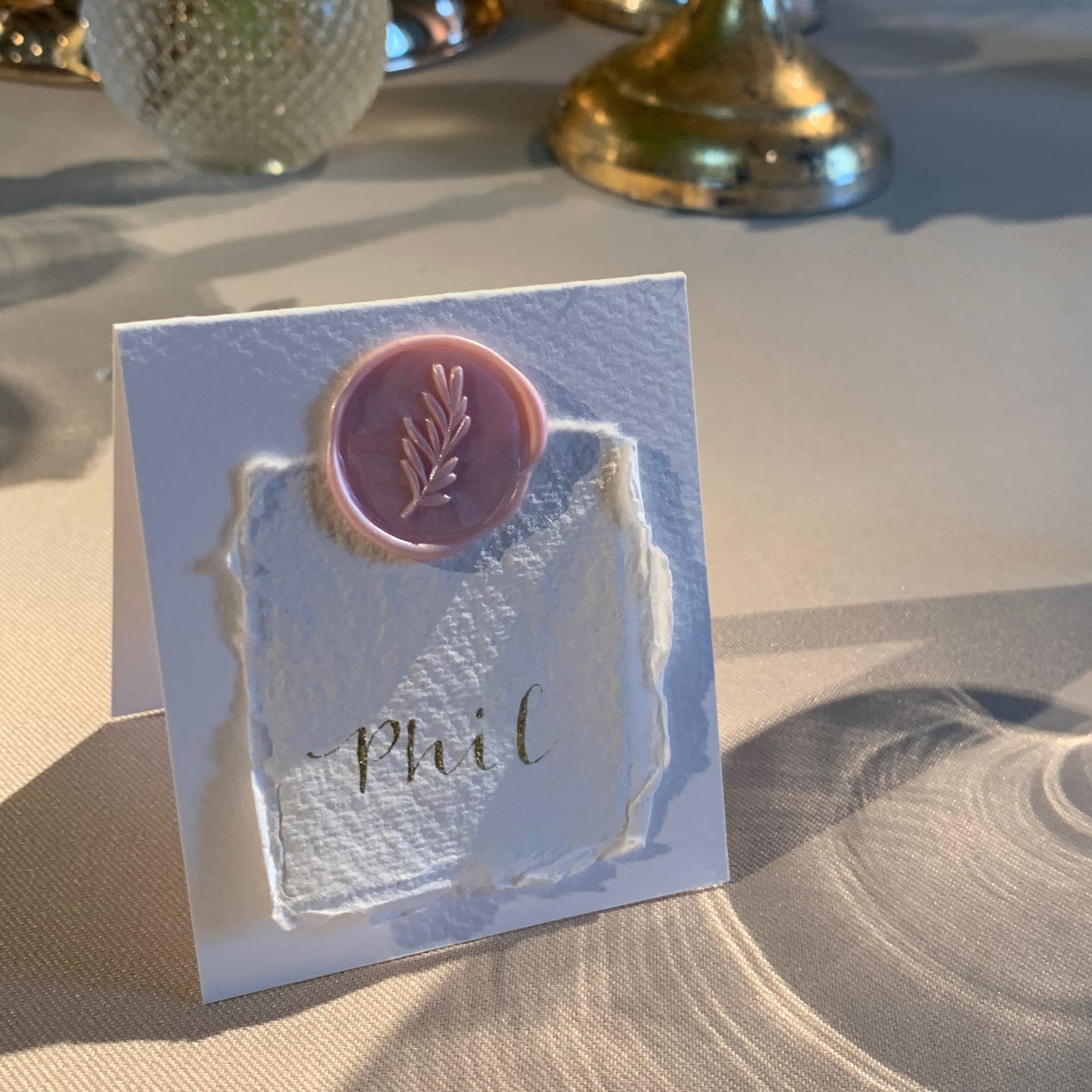 folded place card in white card with pale pink wax seal holding smaller cotton paper with guest name wedding calligraphy