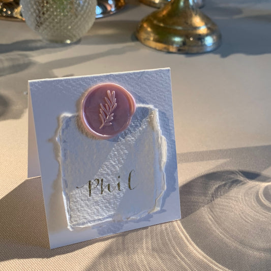folded place card in white card with pale pink wax seal holding smaller cotton paper with guest name wedding calligraphy