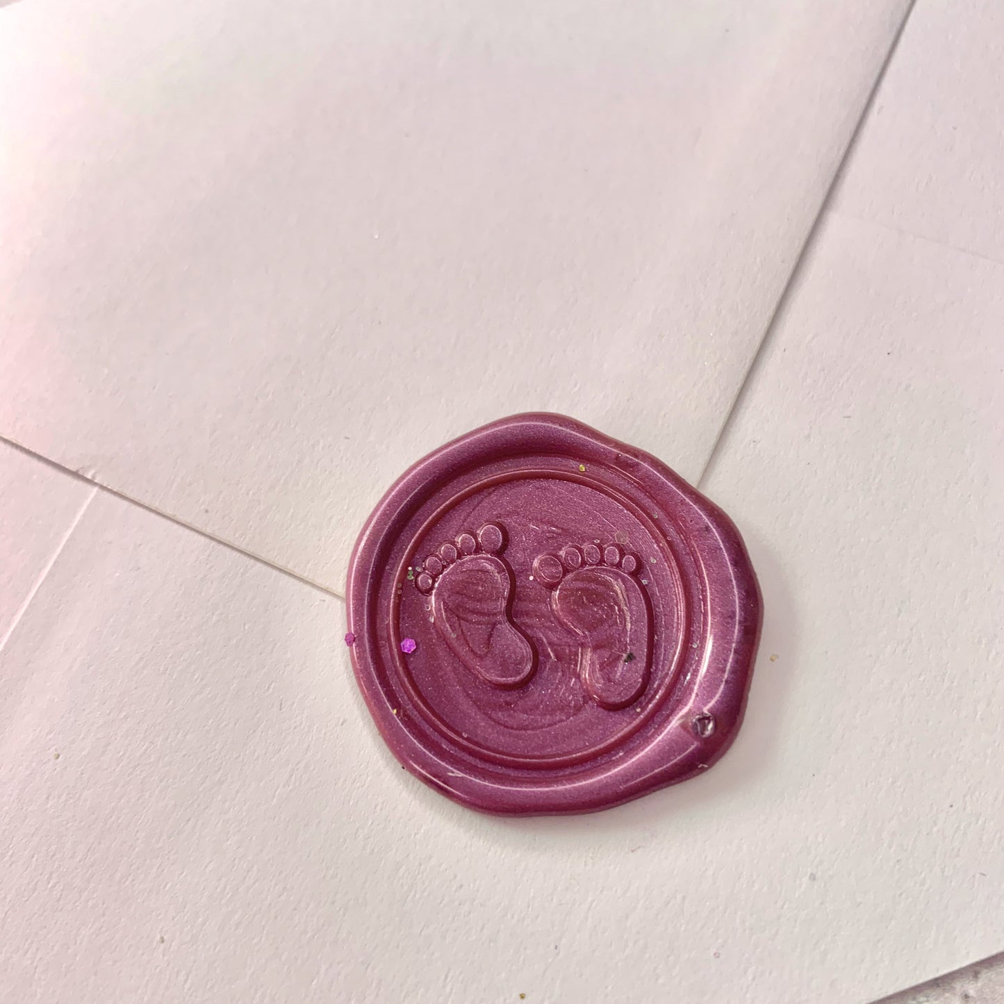 mauve wax seal with baby feet and tiny toes on white envelope