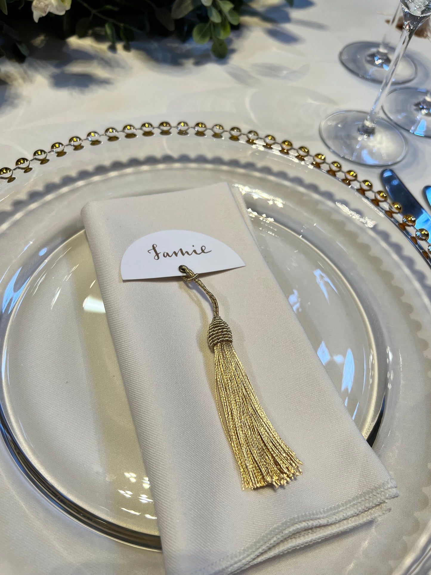 gold ink calligraphy place card - half circle with gold tassel. gold beaded charger plate and ivory napkin