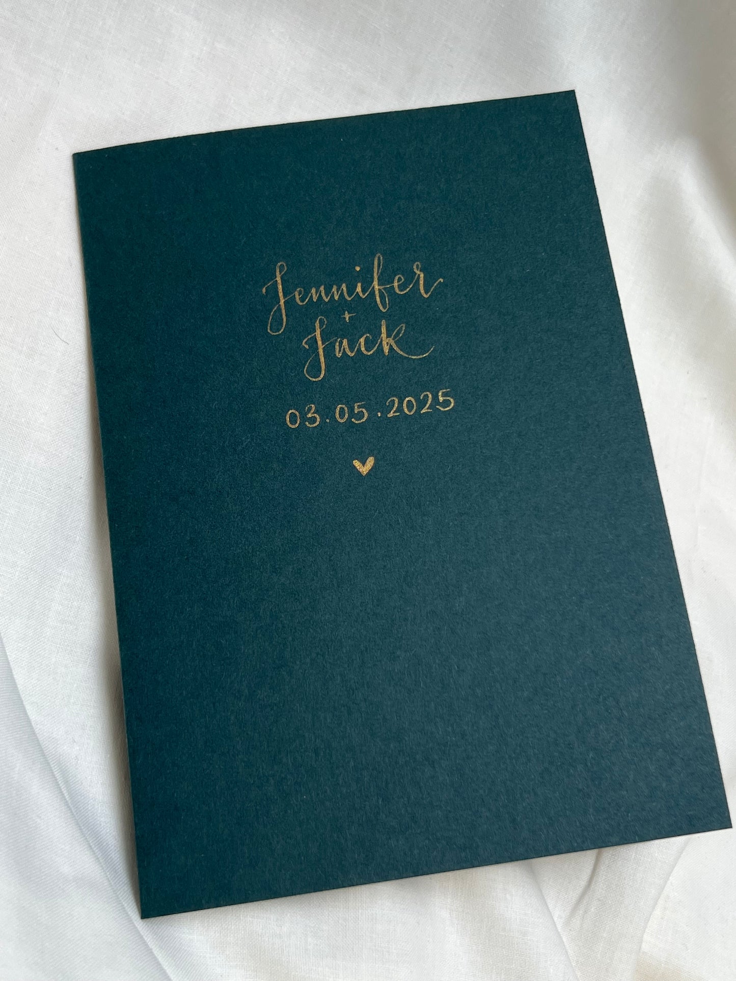 Beautiful wedding day card personalised with bride and grooms names and date of wedding with small gold heart. Handwritten in gold ink calligraphy 