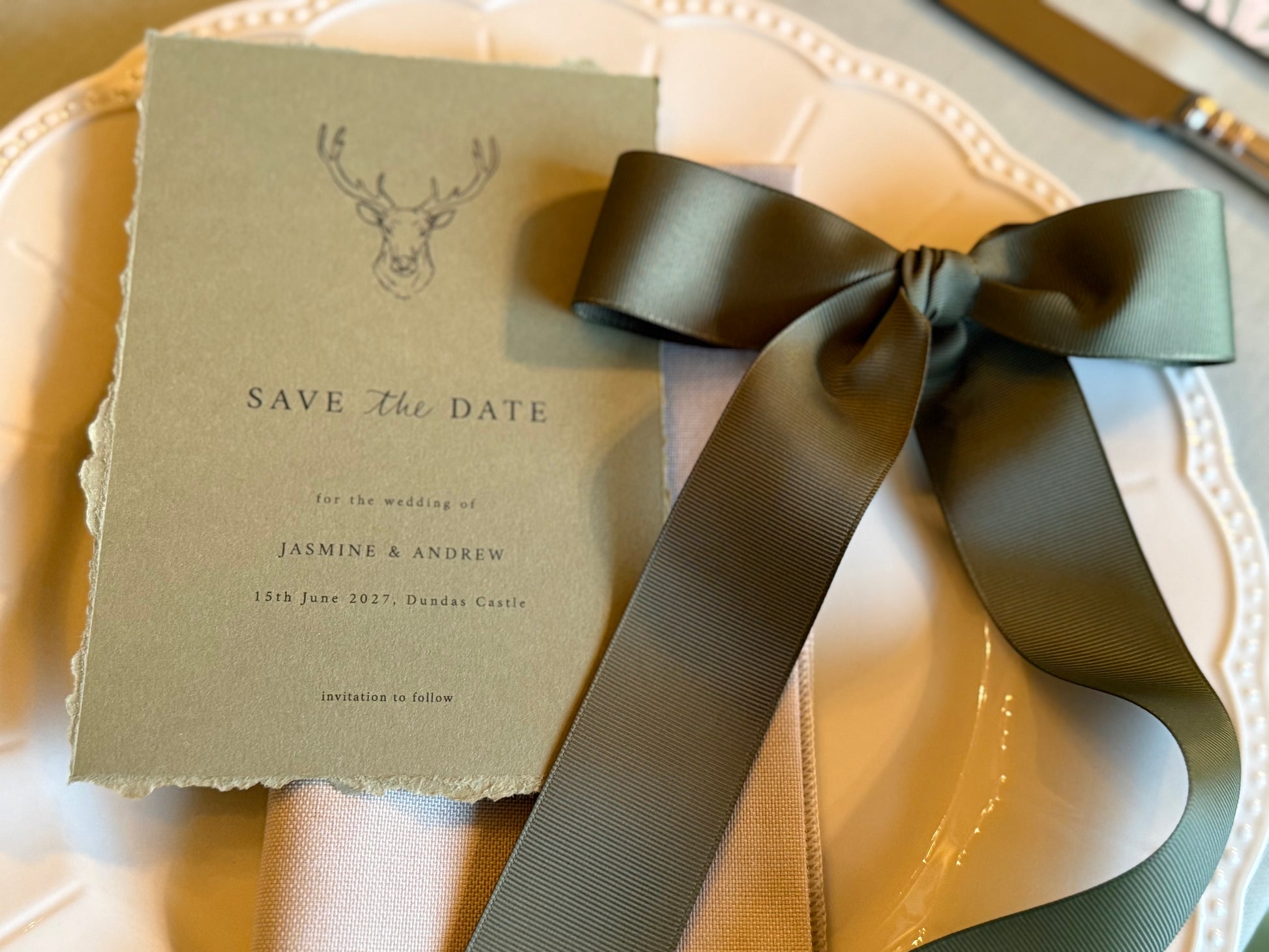 Save the date card with a green ribbon on a white surface