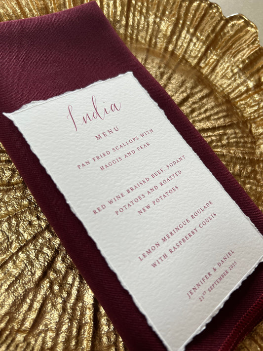 White menu card with red text on a burgundy fabric background