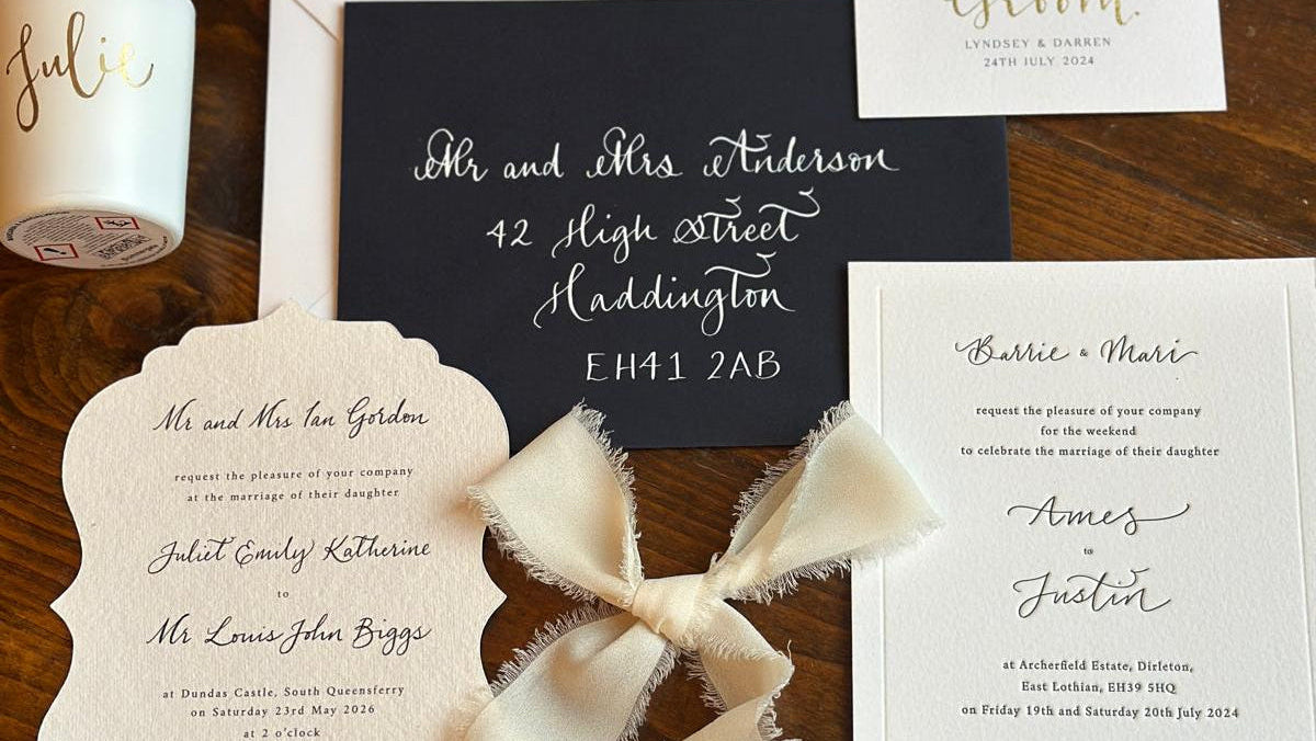 Collection of wedding invitations with ribbons on a wooden surface