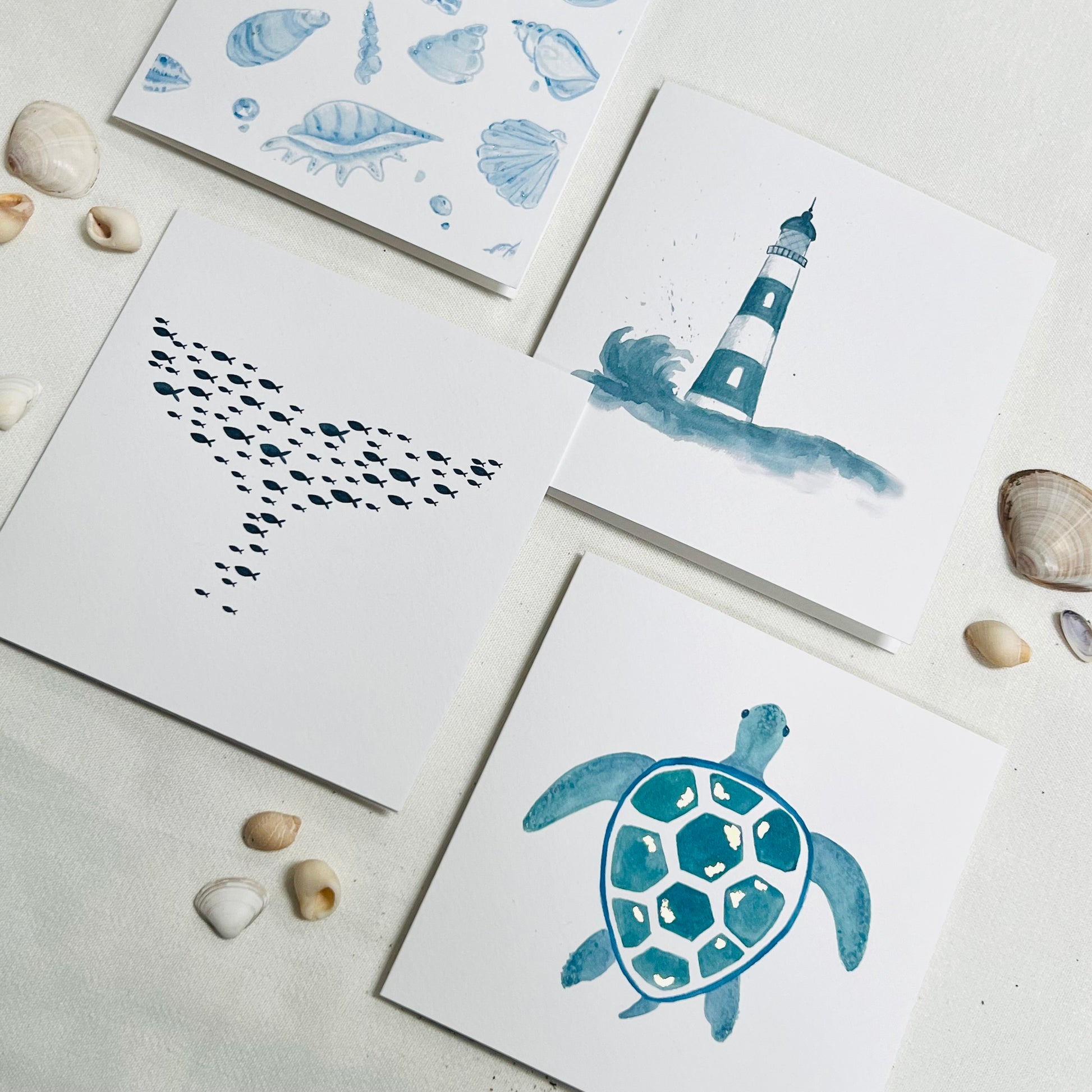 four greetings cards in a sea theme - all blue tones, sea turtles, seashells, whale, lighthouse