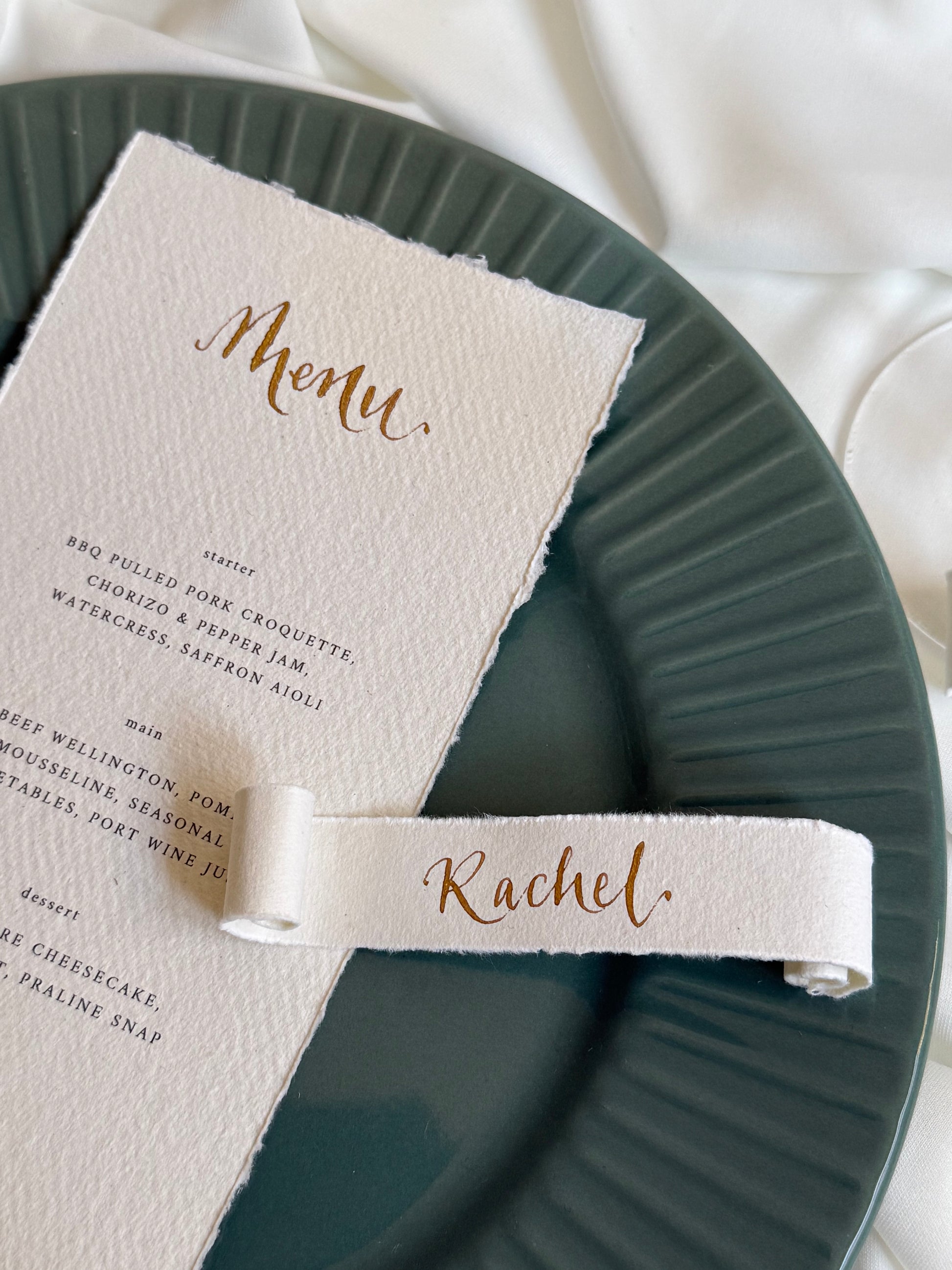 Cotton paper menu card with a scroll name tag on a green plate