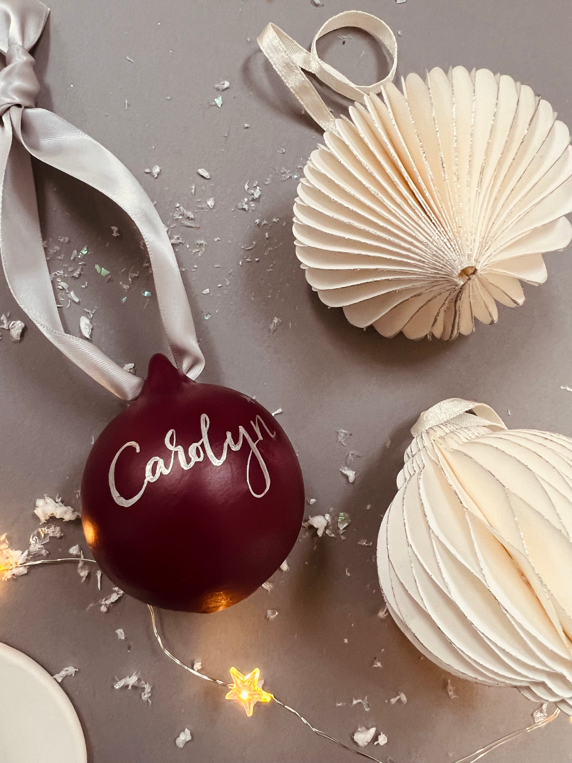 raspberry bauble with hand calligraphed name on a pale silver satin ribbon