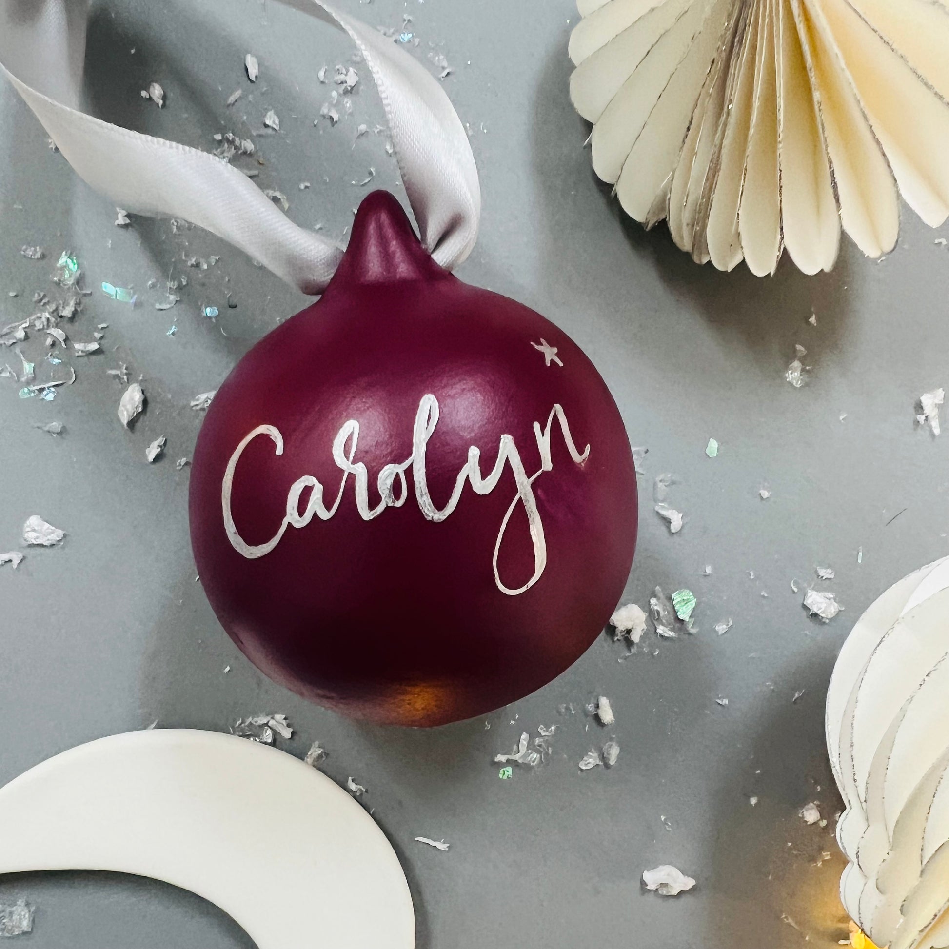 raspberry coloured bauble with handwritten name in calligraphy, using silver metallic ink