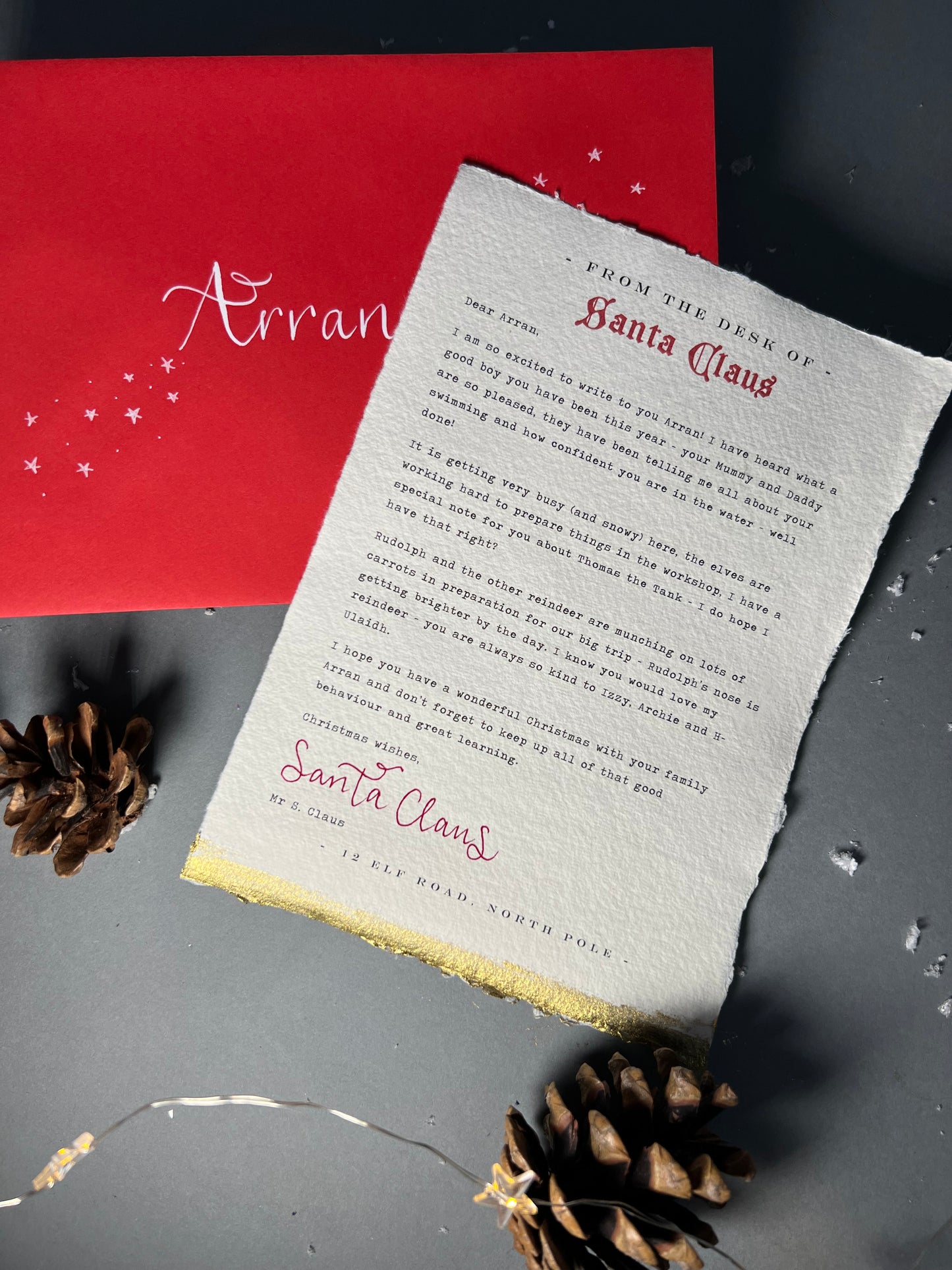 Christmas scene, pinecones and letter with red envelope. Soft edged cotton paper with beautiful printed letter from Santa, hand finished with Santa Claus signature in red ink. Touches of gold to edges of paper. Calligraphy name on envelope in white ink 