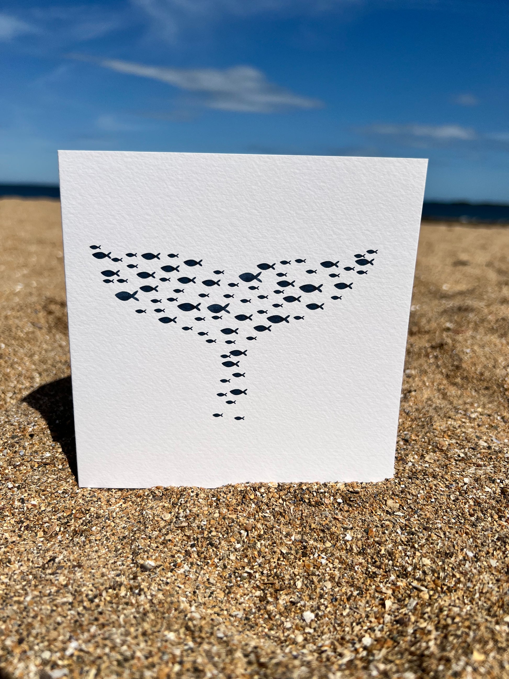 beach picture with greeting card standing on the sand, whale tail made up of lots of small watercolour fish