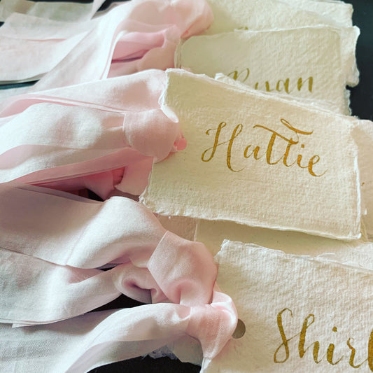 lots of name tags filling image handmade paper gold calligraphy pink faux silk ribbon
