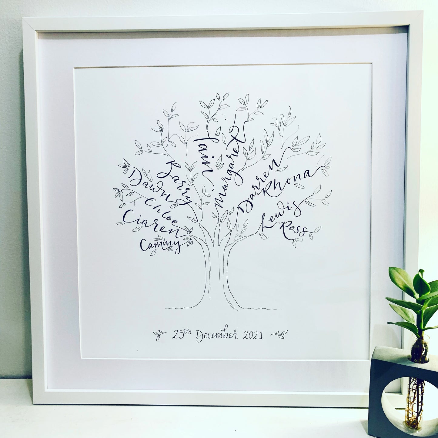 extra large calligraphy family tree black and white in white square frame with mount. Names written to make branches, with hand drawn leaves and tree trunk. Anniversary gift with wedding date at bottom 