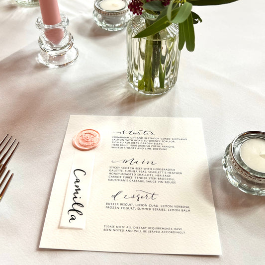square menu with wax seal and tag with guest name in calligraphy handwritten