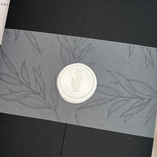 CLOSE UP OF WHITE WAX SEAL WITH FOLIAGE DETAIL ON VELLUM INVITATION CUFF 