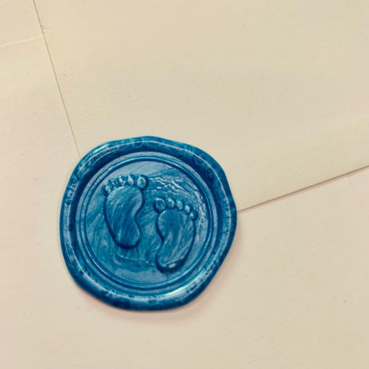 blue wax seal with baby feet design on white envelope