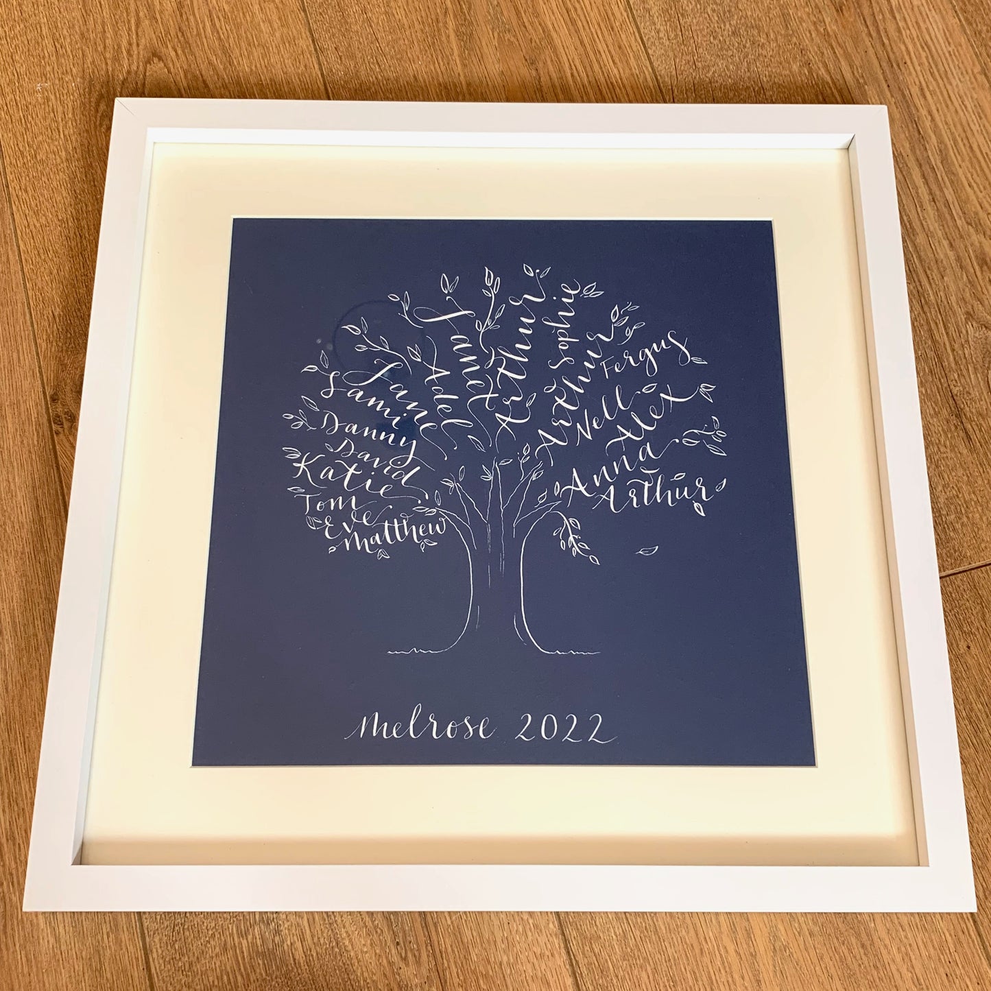 square white frame with off white mount, filled with navy card and white ink calligraphy family tree gift