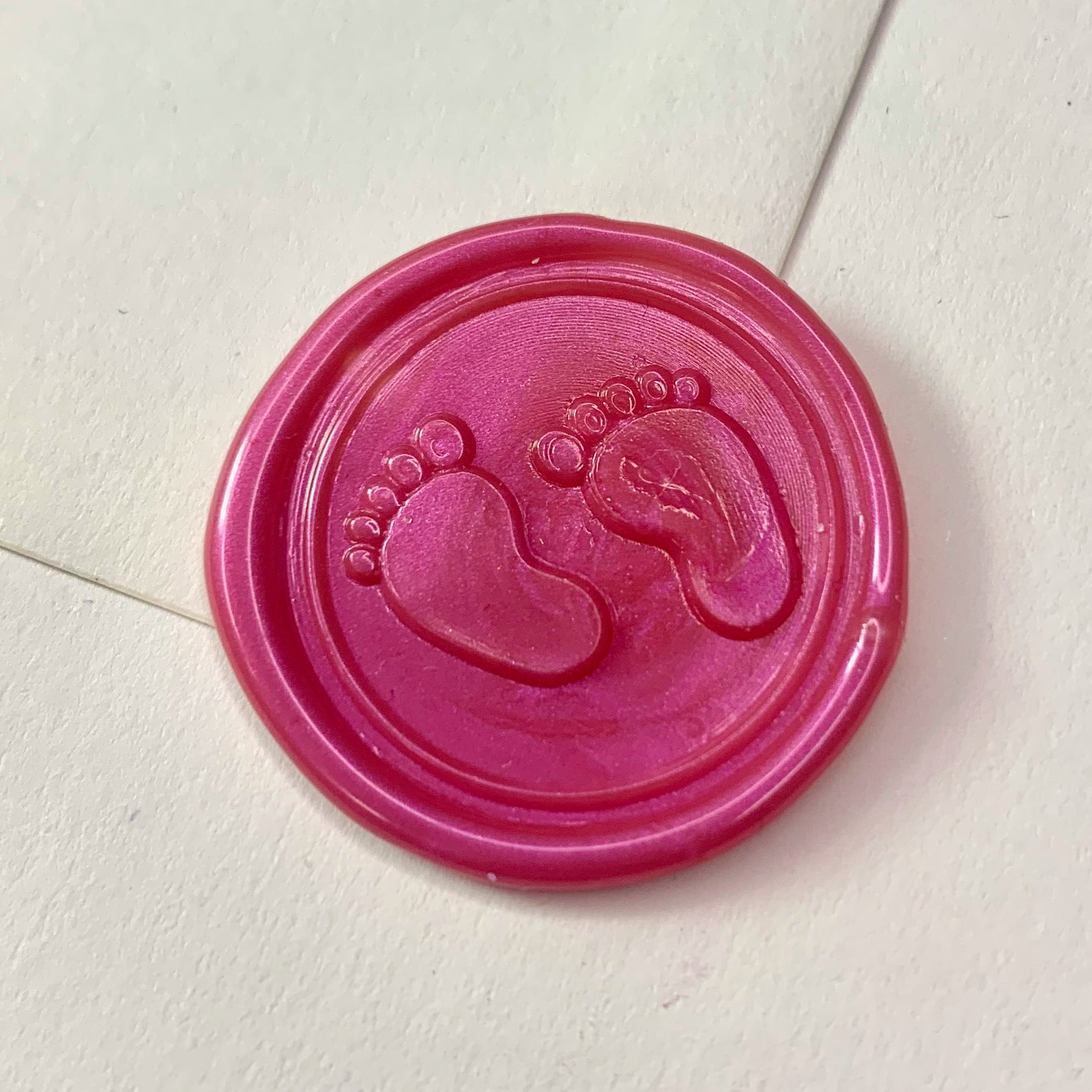 baby feet in pink wax seal on white envelope