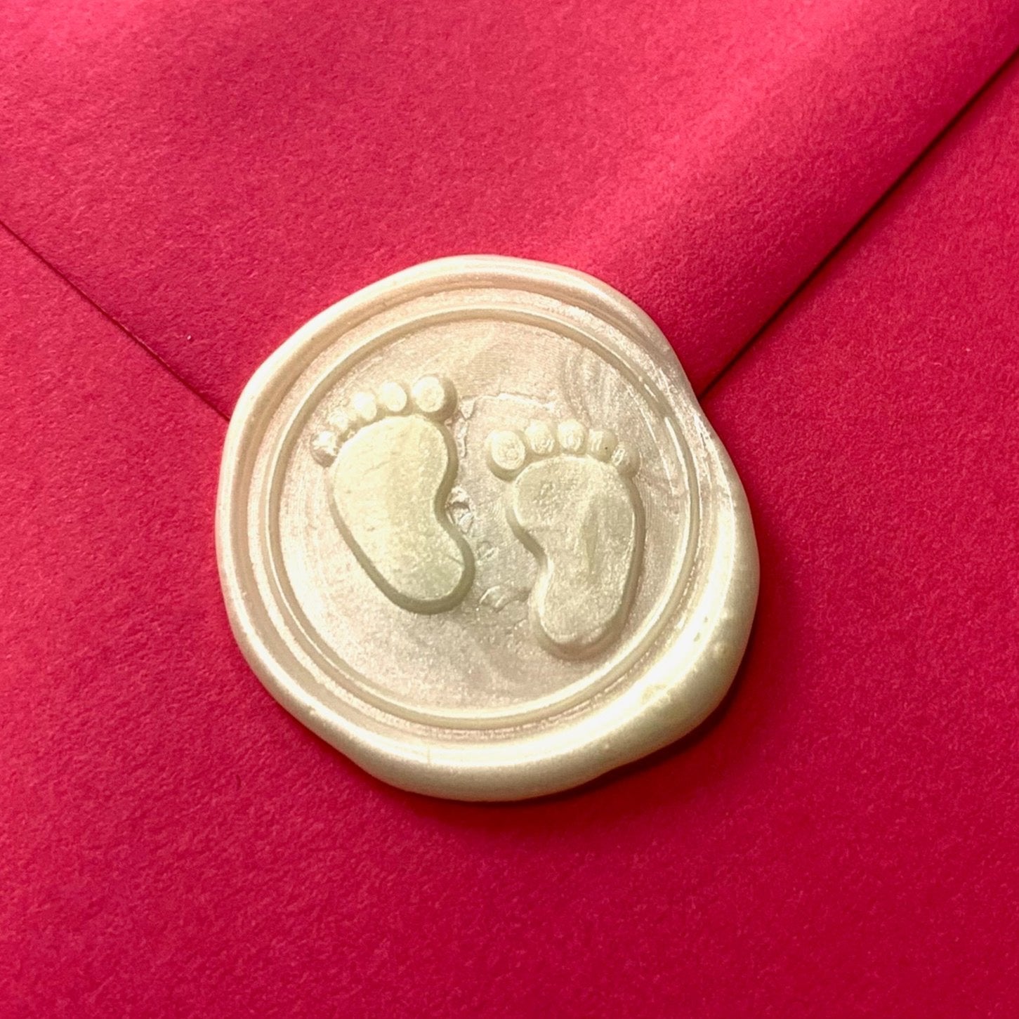 white wax seal on bright pink envelope wax has baby toes and feet design